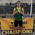 Isabella Maass wearing medals and standing by sectional championship banner