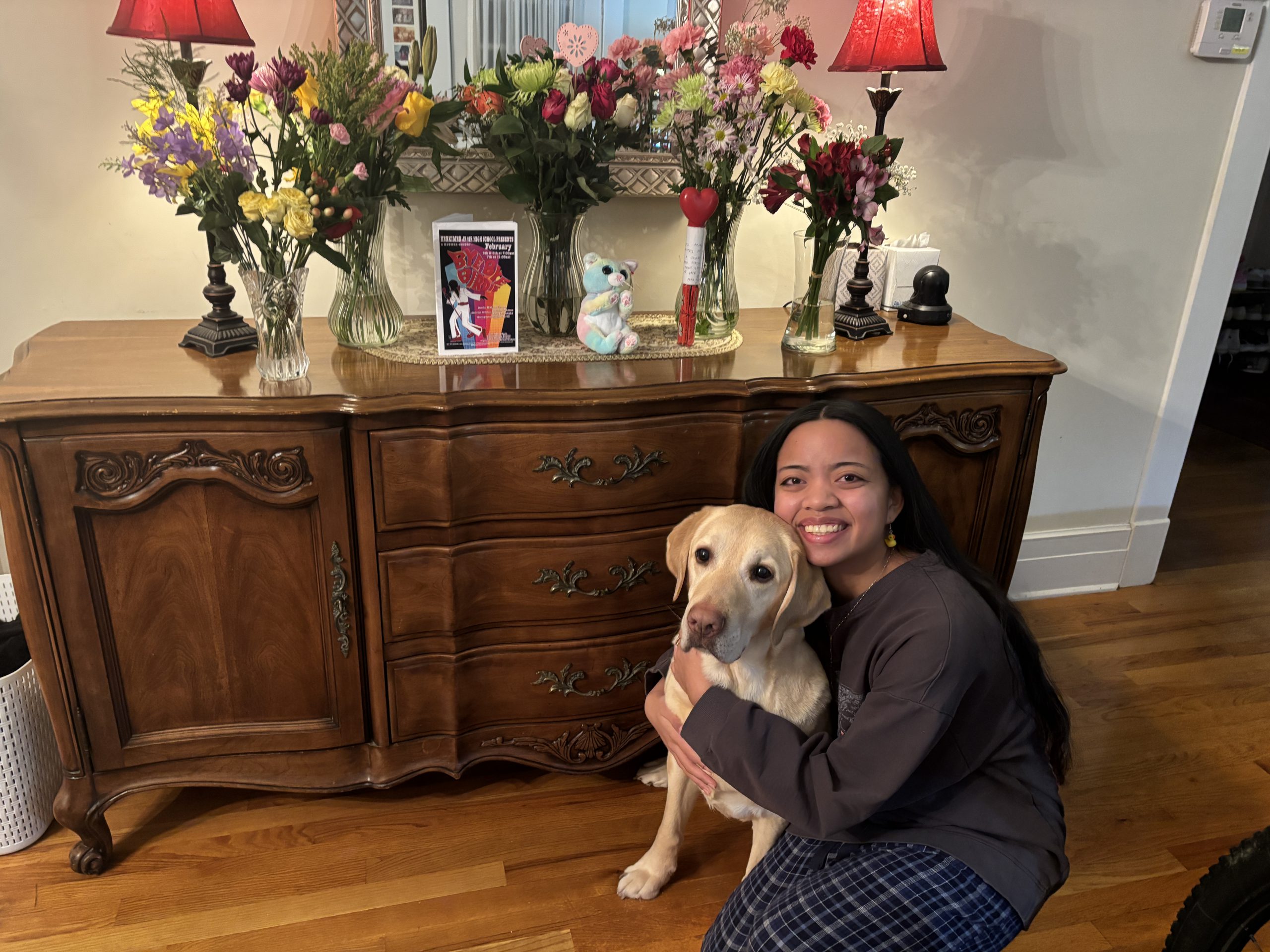 Roselyn Nietes ad a dog next to a dresser with many flowers on it in vases