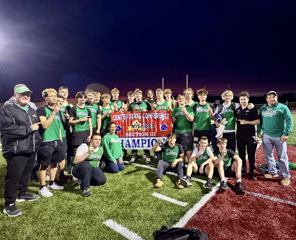 Boys track and field team posing with league championship banner