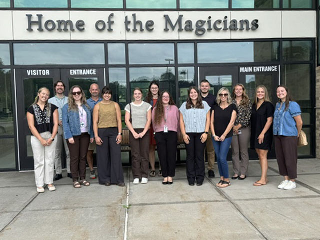 New teachers posing in front of Middle-High School entrance
