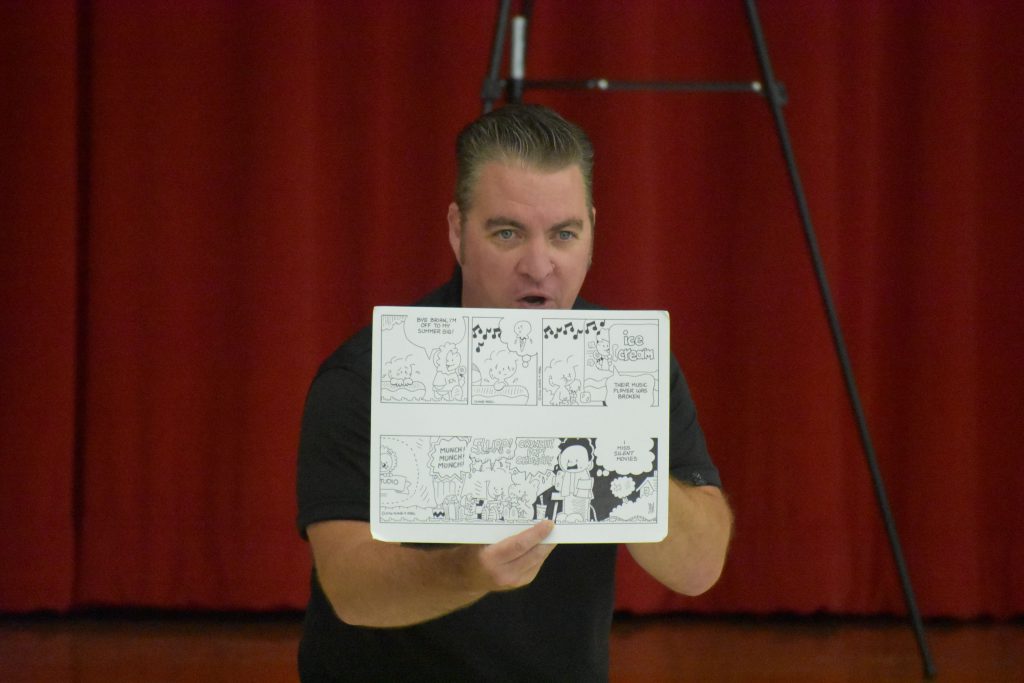 Cartoonist Duane Abel holding up a page of his comic strip