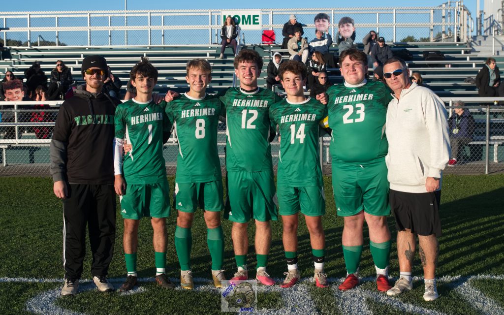 Boys varsity soccer seniors and coaches in front of stands