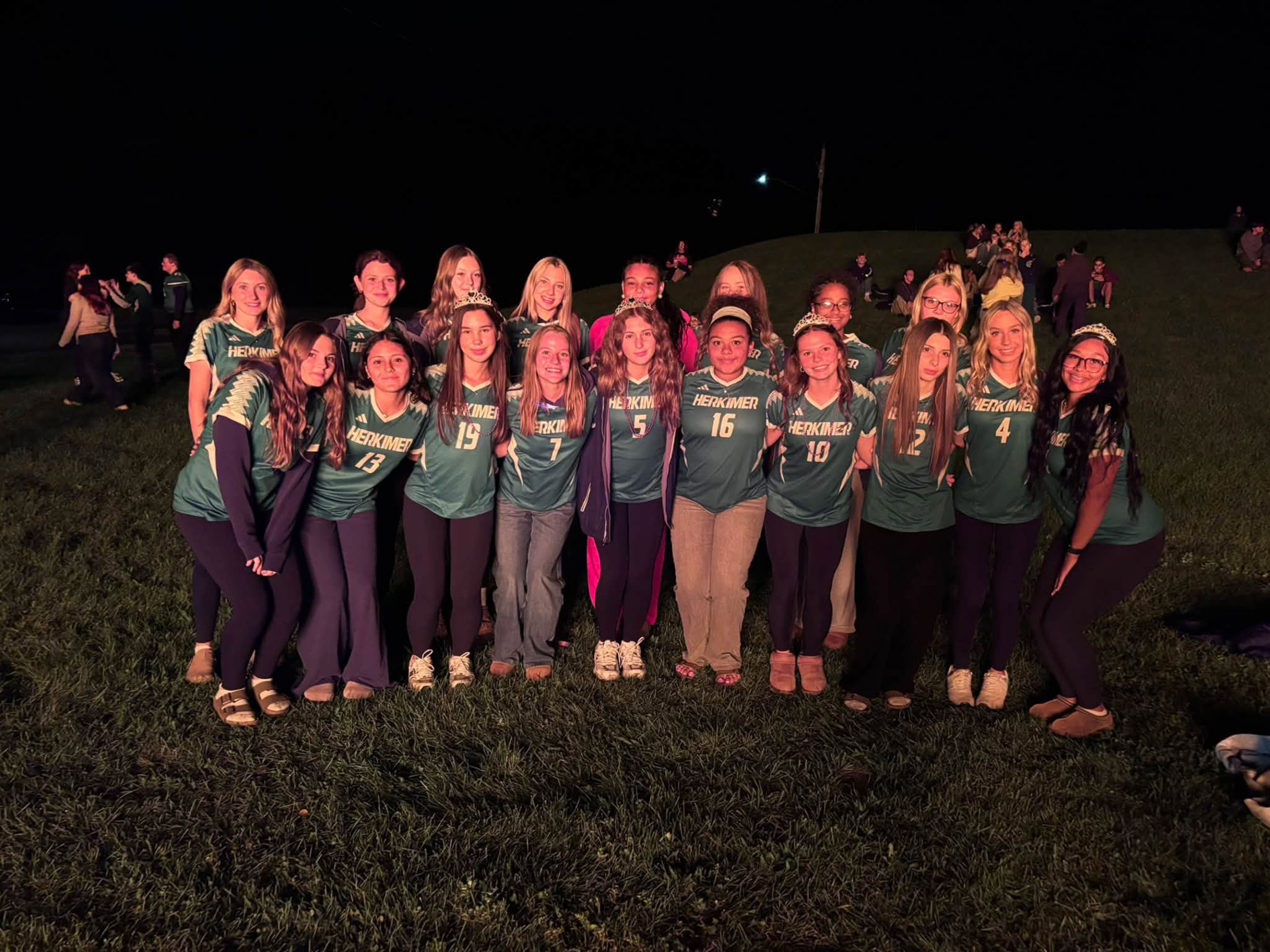 Student athletes posing together outside at night during homecoming
