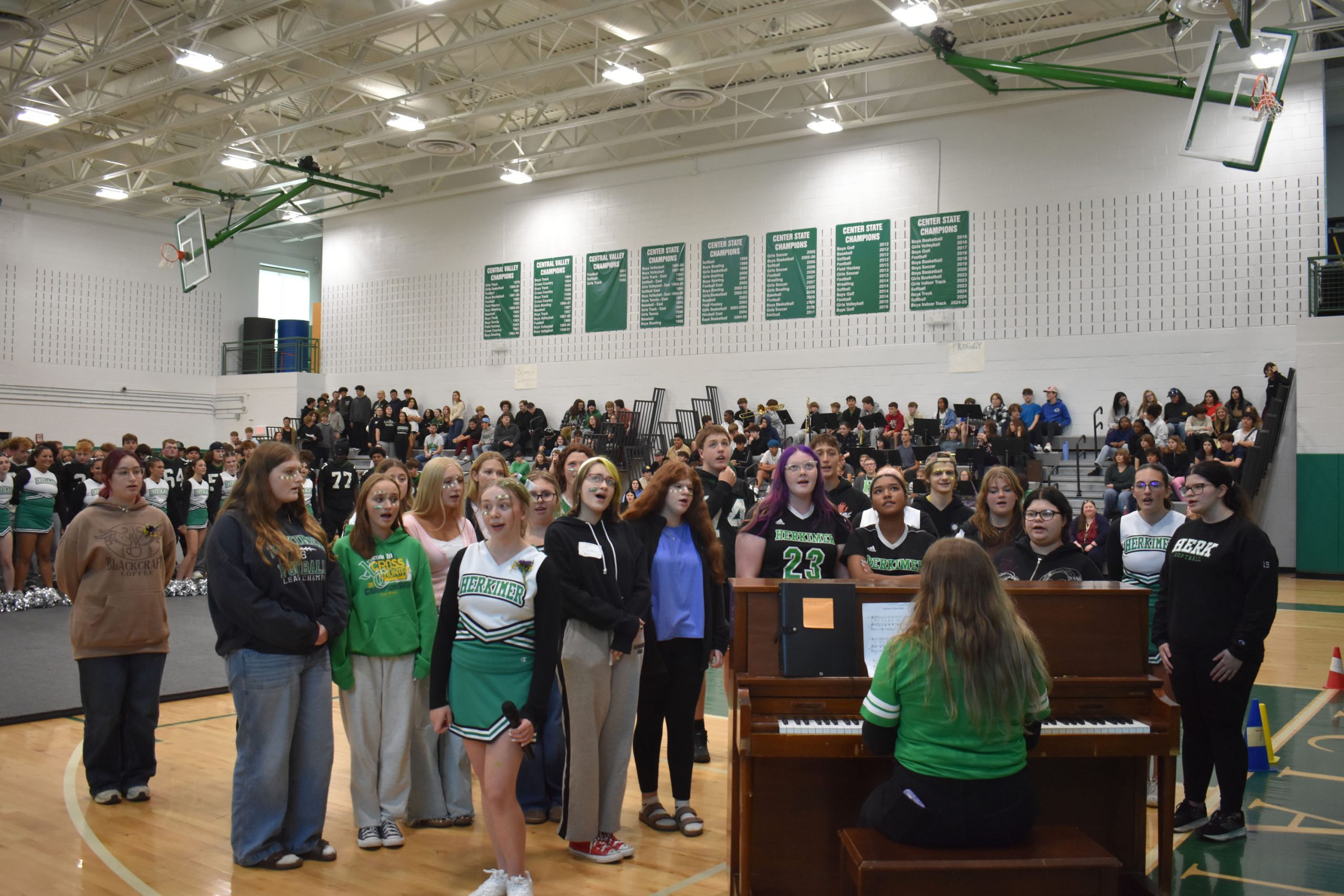 Students singing at pep rally by a piano